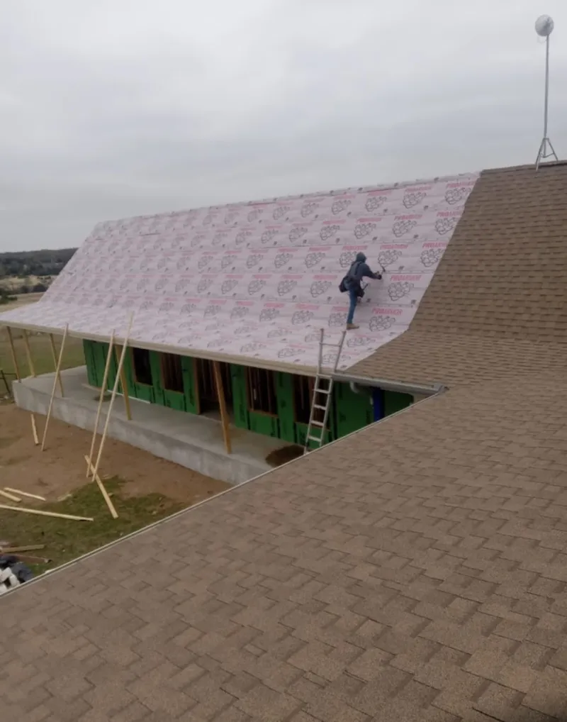 Worker preparing underlayment for a metal roof installation in Portales